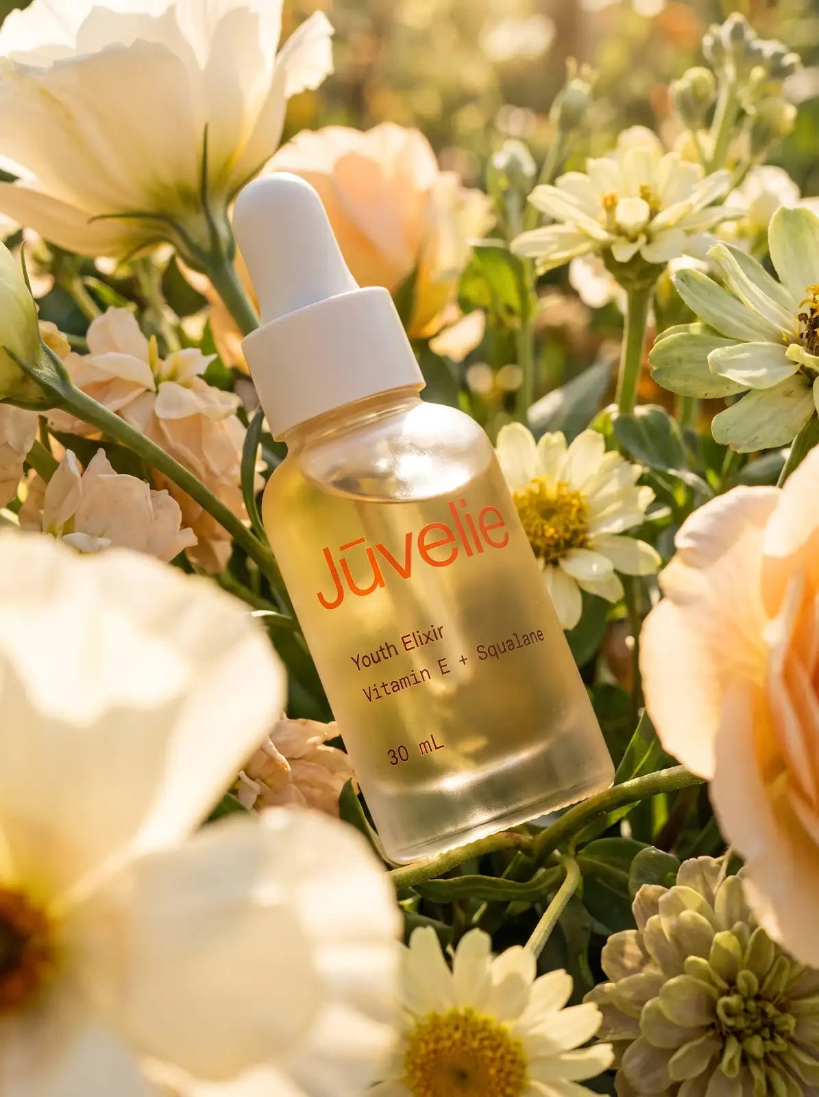Jūvelie Youth Elixir nestled among cream flowers
